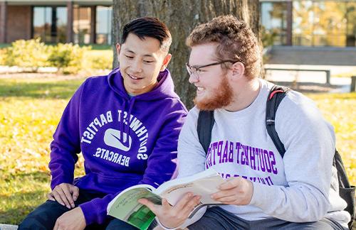 two male students reading a book on SBU 玻利瓦尔 Campus